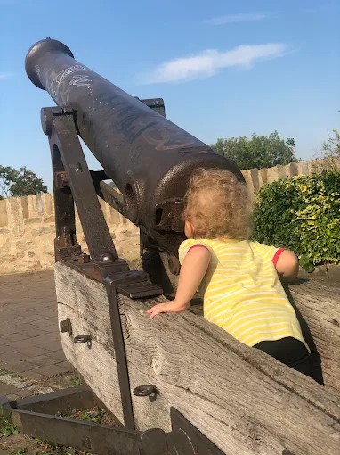 Ein Kind schaut sich eine alte Kanone aus der Nähe an