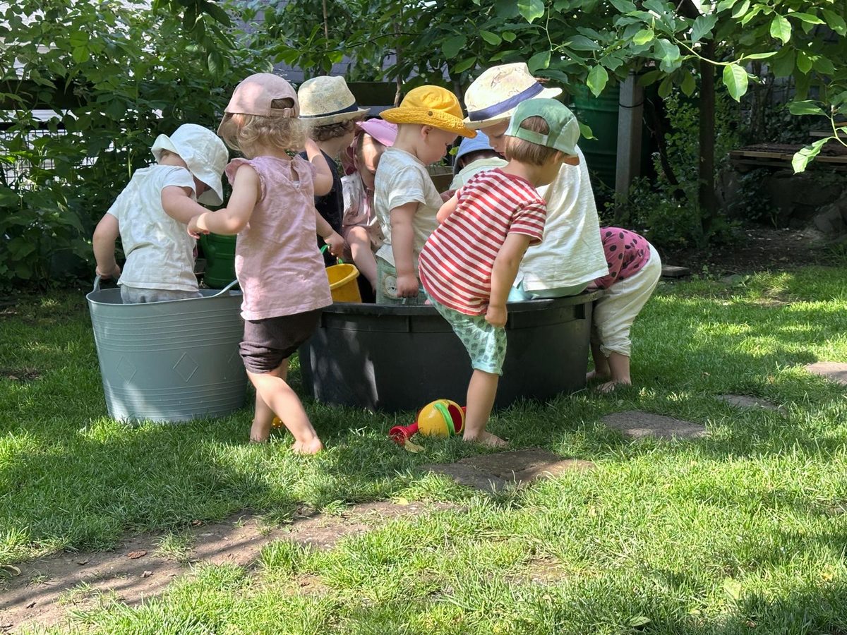 Die Kinder planschen im Garten in großen Wannen