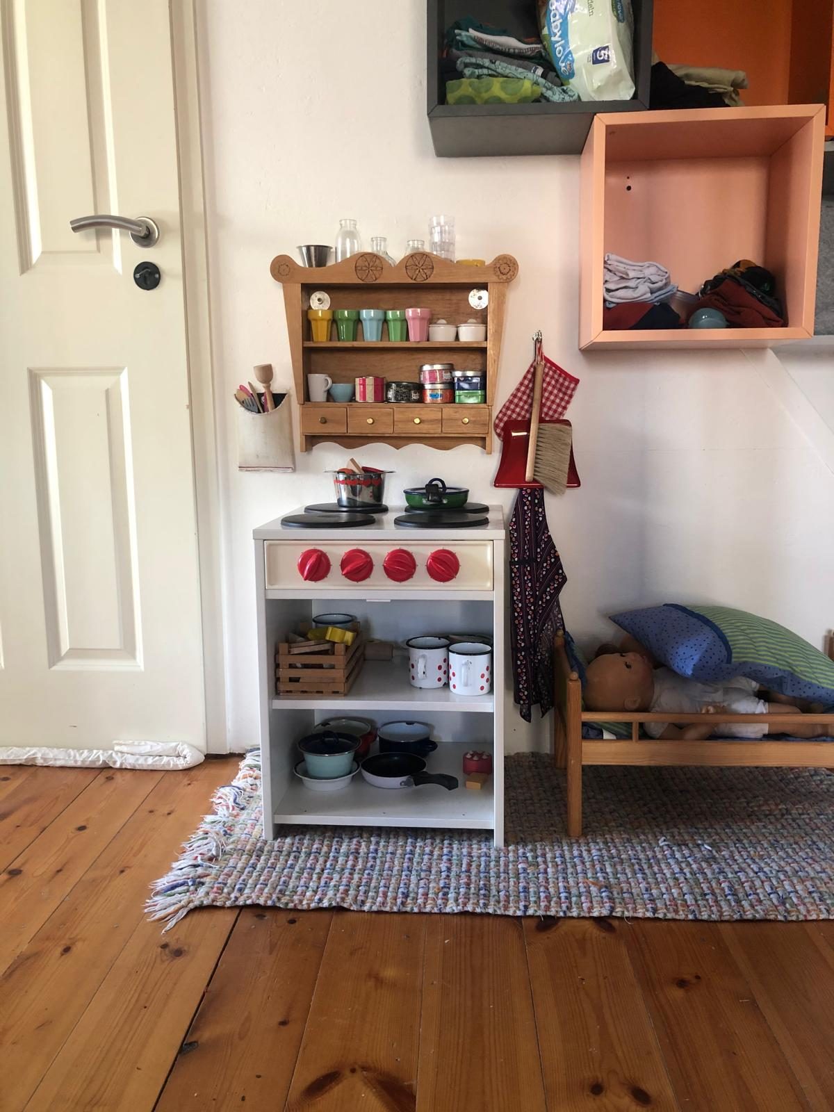 Spielküche mit Töpfen und kleinem Puppenbett